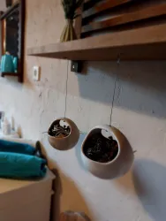 Hängende Blumentöpfe aus Keramik an einer Wand. Der Hintergrund zeigt eine helle Wand und einige alltägliche Gegenstände.