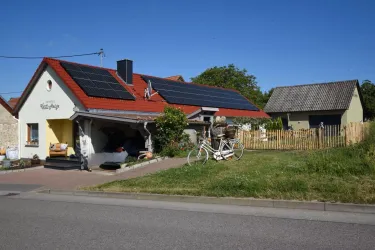 Ein hübsches Haus mit roten Ziegeln und Solarpanels auf dem Dach.