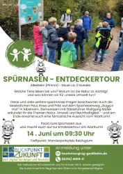 Eine Gruppe von Kindern und Erwachsenen steht in der Natur und erkundet die Umgebung. Es gibt Informationsschilder und die Veranstaltung heißt "Entdeckertour".