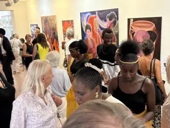 Eine lebhafte Kunstausstellung mit vielen Besuchern, die abstrakte Gemälde betrachten. Die Atmosphäre ist freundlich und bunt, mit Menschen in verschiedenen Outfits.