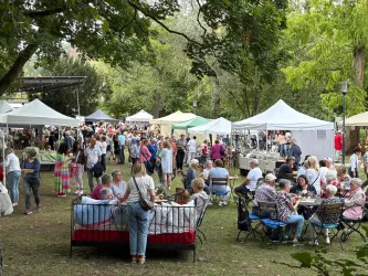 Ein belebter Markt im Freien mit vielen Ständen und Besuchern. Die Atmosphäre ist lebhaft und gesellig.