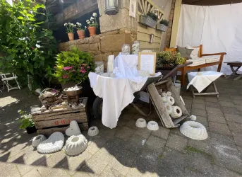 Eine kleine Marktbude mit verschiedenen Dekorationsgegenständen. Auf einem Tisch sind Blumentöpfe, Geschirr und andere Handwerksartikel ausgestellt.