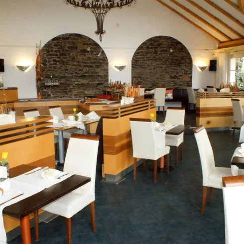 Ein stilvolles Restaurant mit modernem Ambiente. Die Tische sind elegant gedeckt, und große Fenster sorgen für viel Licht.