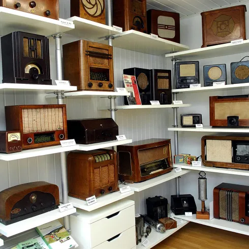 Ein Raum voller antiker Radiogeräte aus verschiedenen Epochen. Die Geräte sind auf Regalen ausgestellt und zeigen eine Vielzahl von Designs und Stilen.