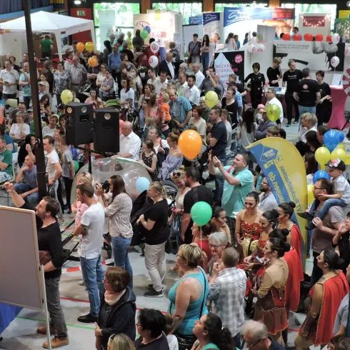 Eine große Menschenmenge bei einer Veranstaltung. Viele Besucher stehen und schauen sich die Stände an.