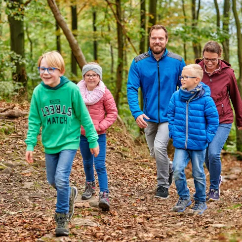 Familie mit drei Kindern wandert durch den Wald.
