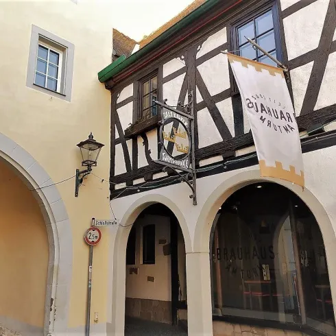 Ein charmantes Fachwerkhaus mit einem großen Schild über dem Eingang. Es ist eine malerische Gasse mit historischen Elementen.