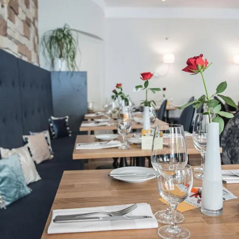 Ein geschmackvoll eingerichteter Restaurantbereich mit eleganten Tischen und dekorativen Rosen. Die Atmosphäre ist einladend und stilvoll.
